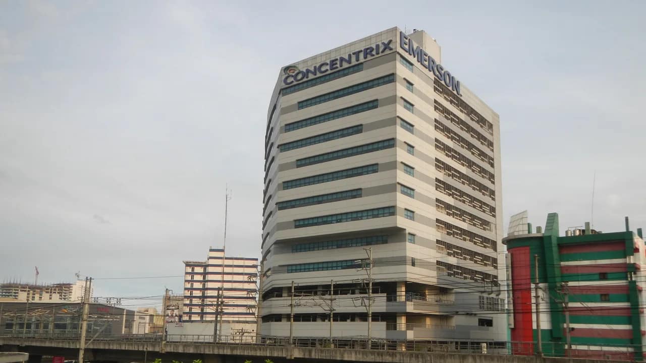 Gedung kantor di Quezon City, Filipina, dengan logo Concentrix dan Emerson di puncaknya, terlihat dari seberang jalur kereta layang di North Avenue.